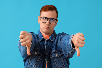 Young man showing dislike on blue background