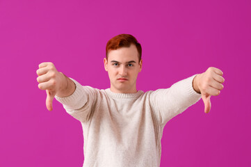 Young man showing dislike on purple background