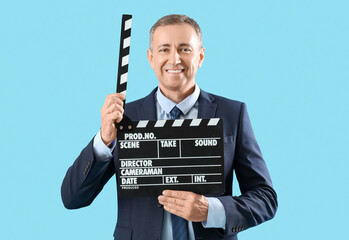 Mature actor with movie clapper on blue background