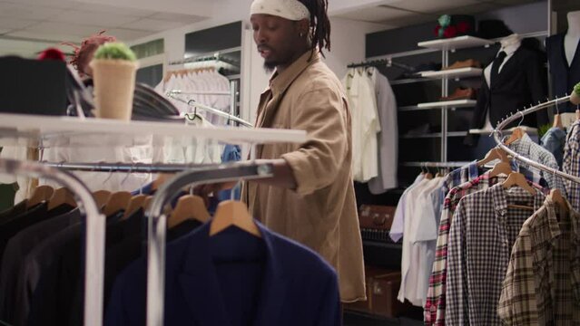 Fashion consultant commissioned to help client build his wardrobe, shopping together in thrift shop for vintage clothes. Specialist assisting client in finding perfect fit in premium SH store