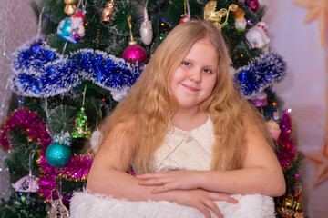 A beautiful elegant girl near the Christmas tree in the New Year. Holiday. New Year. The child is a model.