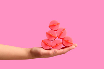 Female hand with curlers on pink background.