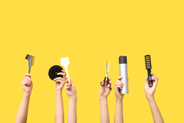 Many female hands with hair supplies on yellow background.