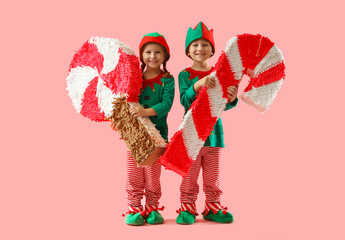 Cute little elves with candy pinatas on pink background