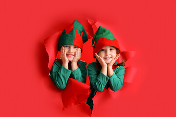 Cute little elves visible through torn red paper