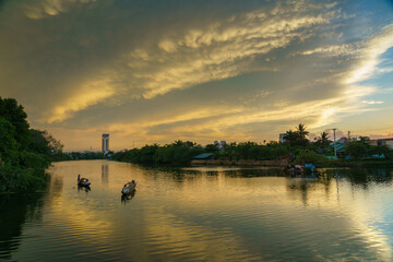 Fototapeta premium River view in Hue with traditional wooden boats and dramatic sunset sky in Hue city, Vietnam
