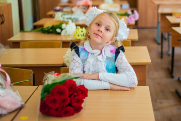 The first time in the first class! A first-grader girl in a beautiful elegant modern school uniform on the Day of Knowledge at school.
