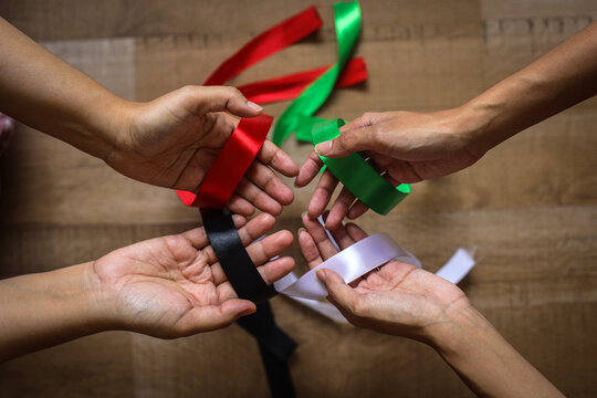 People's hands holding colorful ribbons, red, black, white and green to represent Palestinian flag