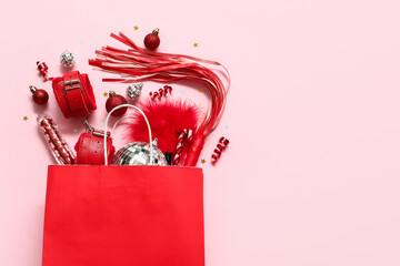 Paper bag with Christmas decor and sex toys on pink background