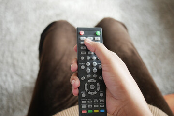 close up of women hand holding tv remote.