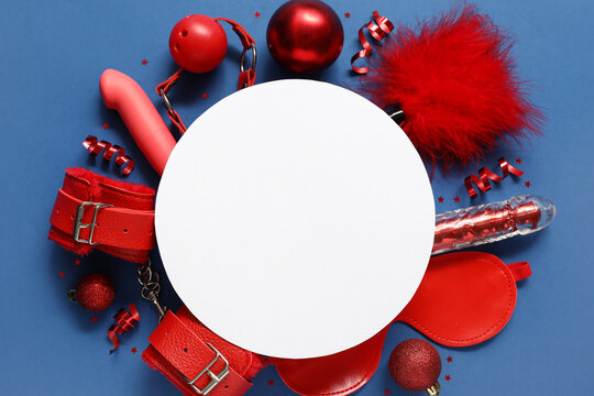 Blank card with Christmas decor and sex toys on blue background