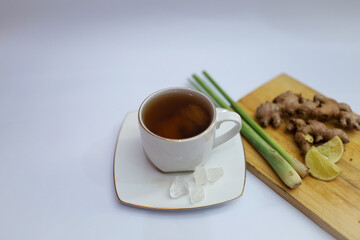 A cup of hot ginger tea with ginger root and lemongrass and rock sugar.  the concept of herbal drinks for body warming and throat lozenges