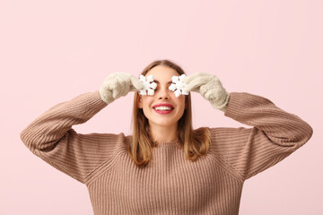 Happy young woman with decorative snowflakes on pink background