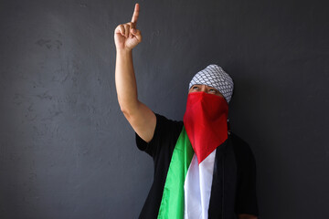Man with Palestine flag raising one finger and pointing above as a symbol for tawheed