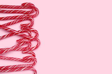 Many Christmas candy canes on pink background