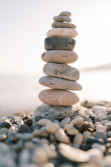 Fototapeta na wymiar Cairn stands on a pebble beach in bright sunlight