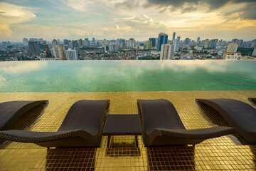Relaxing chairs on Infinity pool with Hanoi skyline on background