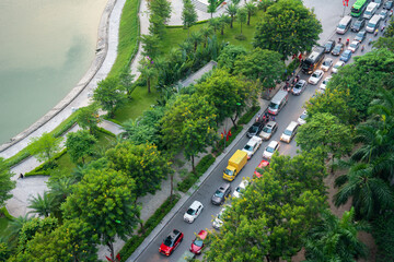 Aerial view of Hanoi traffic with vehicles on street among green tree lines by a lake