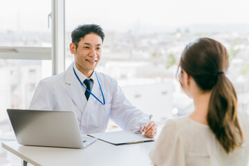 Obraz premium 診察・診療・問診・カウンセリングをする医者・医師・ドクターの男性と女性 