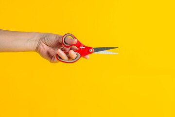 Office stationery scissors cutting in hand on yellow background