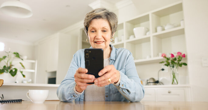 Happy senior woman, phone and social media in relax for communication or networking in kitchen at home. Mature female person smile on mobile smartphone for online chatting, texting or search at house - Powered by Adobe