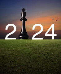 2024 white text with black chess king on green grass field over sunset sky with birds, Happy new...