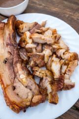 A serving of a piece of Liempo, or grilled pork belly, both chopped and whole and served with gravy.