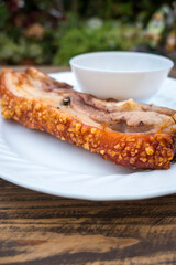 A serving of a piece of Liempo, or grilled pork belly, served with gravy.