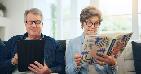 Senior couple, reading book and tablet on sofa in home, relax and internet search on social media. Elderly man, woman and technology, knowledge and information in living room in retirement together - obrazy, fototapety, plakaty