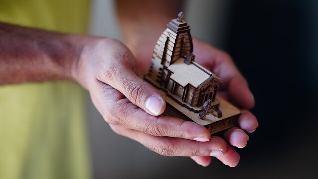 hands holding a wooden figure of kedarrnath dham