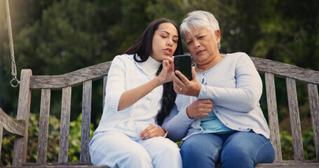 Phone, senior or mother with woman on bench in nature reading news on social media in retirement. Online gossip, mature parent or daughter for together in park or garden as a family with mobile app - obrazy, fototapety, plakaty