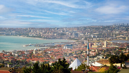 Fototapeta premium Aerial view of a modern city with a sea bay against a background of a beautiful sky with clouds.