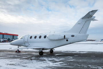Fototapeta na wymiar White executive airplane at winter airport apron