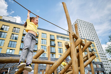 A girl hangs on a rope from a wooden sports complex.