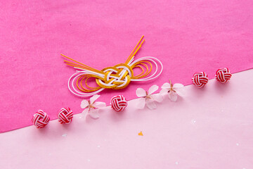 日本の正月イメージ　桜の花と2種類の水引と和紙のデザイン（ピンクとホットピンクの和紙の背景）
