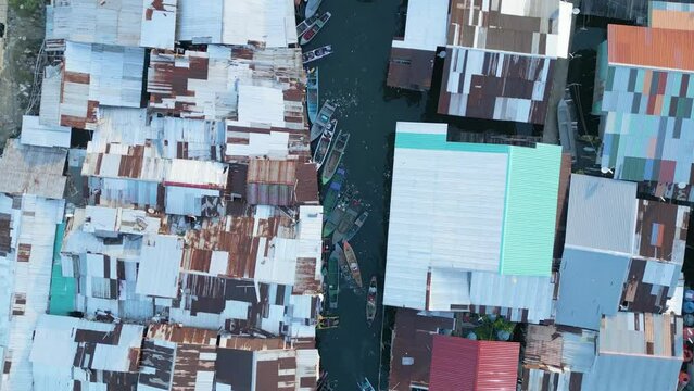 Bird-eye aerial over the Sabah Semporna Bajau Laut community, Malaysia. Residential settlement  with houses located on and near the beach. Rooftops and boats on the water.