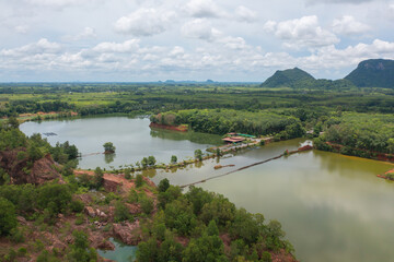 Fototapeta premium Aerial top view of a bridge with garden park with green mangrove forest trees, river, pond or lake. Nature landscape background, Thailand.