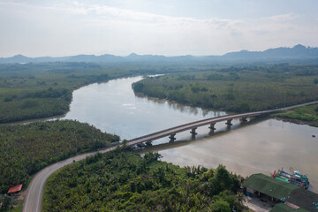 Fototapeta premium Aerial top view of a bridge with garden park with green mangrove forest trees, river, pond or lake. Nature landscape background, Thailand.