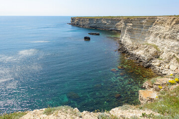 Fototapeta premium Cape Tarkhankut on the Crimean peninsula. The rocky coast of the Dzhangul Reserve in the Crimea. The Black Sea. Turquoise sea water. Rocks and grottoes of Cape Tarkhankut.