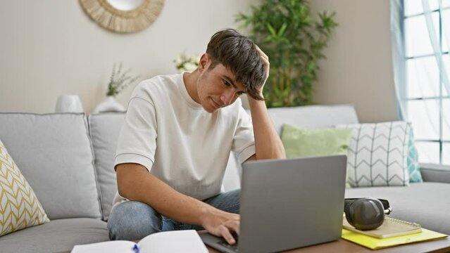 Stressed out young hispanic teenager sitting, studying on his laptop at home, face focused, struggling with online education on the living room sofa