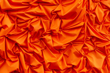 Orange silk crumpled fabric as an abstract background. Texture