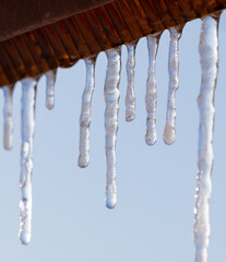 Icicles hang from the roof against the blue sky