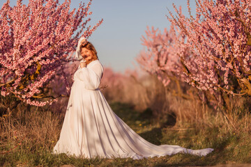 Woman blooming peach orchard. Against the backdrop of a picturesque peach orchard, a woman in a...
