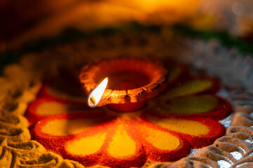 diwali diya or oil lamp lit on colorful rangoli. closeup shot of diwali diya 