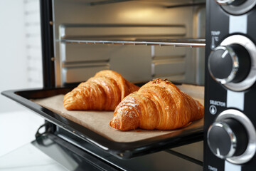 Modern mini electric oven with freshly baked croissants in kitchen