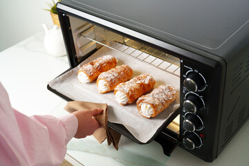 Woman's hands taking fresh bakery out of mini oven