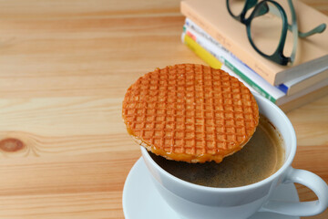Hot Coffee with Stroopwafel Placed on Top of the Cup on Wooden Table