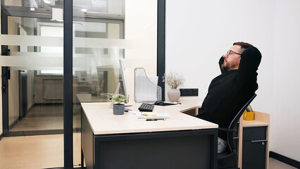 Modern office businessman working on a computer. Portrait of a successful Latin software engineer working on a laptop at his desk. Diverse workplace with professionals.