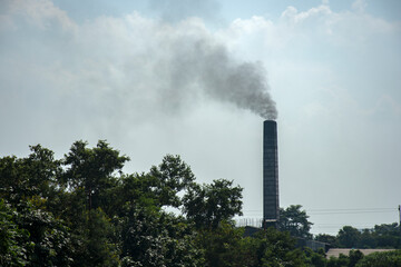 Very dirty dark smoke comes out in horrific clouds from old chimney of factory plant, polluting environment. Toxic production company. Industrial enterprise.