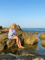 Woman relaxing on rocks by the sea